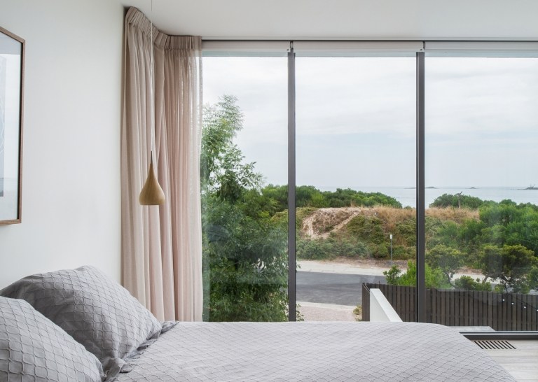 Quarto com cortinas de vidro rosa com vista para as dunas de areia