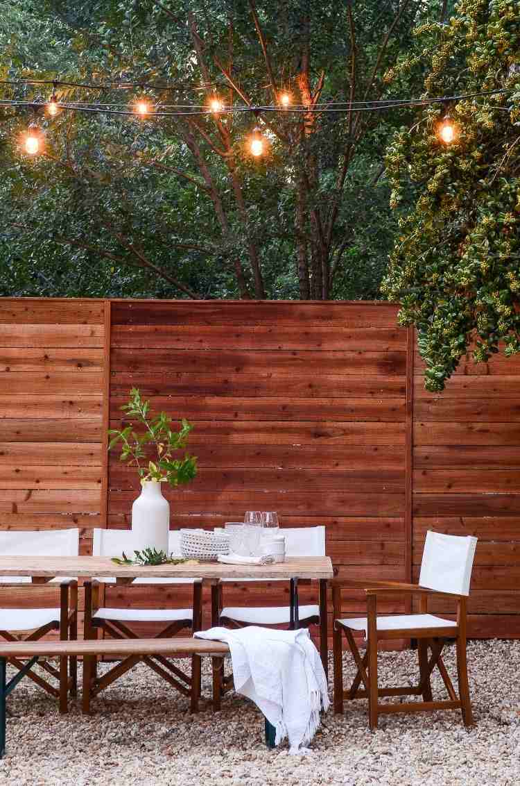 mesa de jardim elegante e aconchegante com uma cerca feita de ripas de madeira e luzes