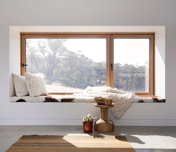 Construir janelas salientes e organizar assentos com um cobertor aconchegante, almofada de assento e mesa de centro
