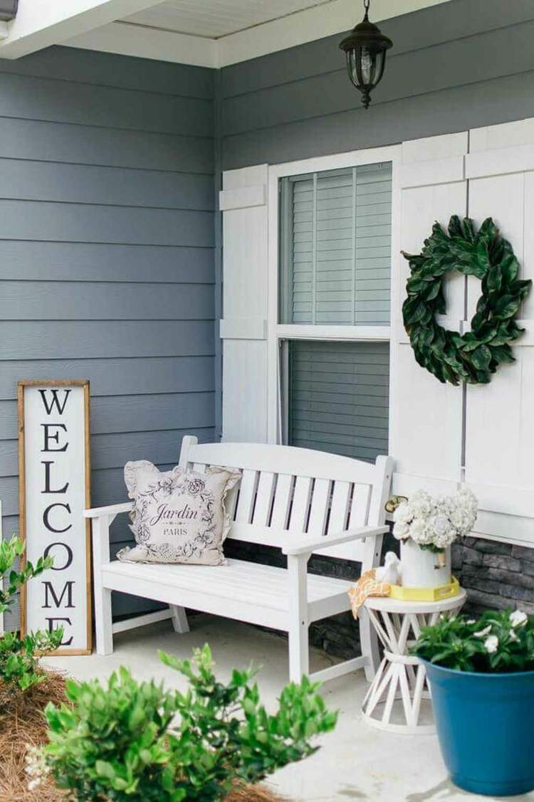 Decoração simples em branco para a varanda com placa de boas-vindas, banco e mesa lateral