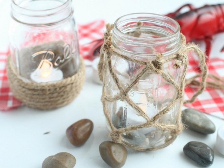 A mesa de jantar com decoração de verão faz vasos ou lanternas com potes de geléia e macramê