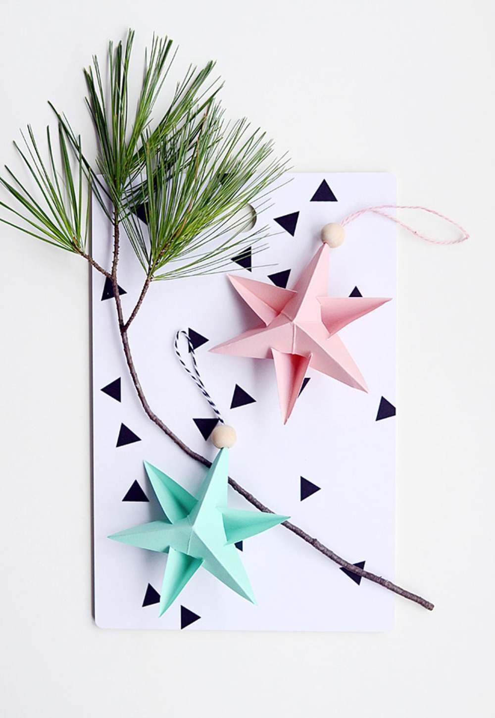 Ramo de abeto com duas estrelas de papel em rosa e verde menta como decoração de Natal