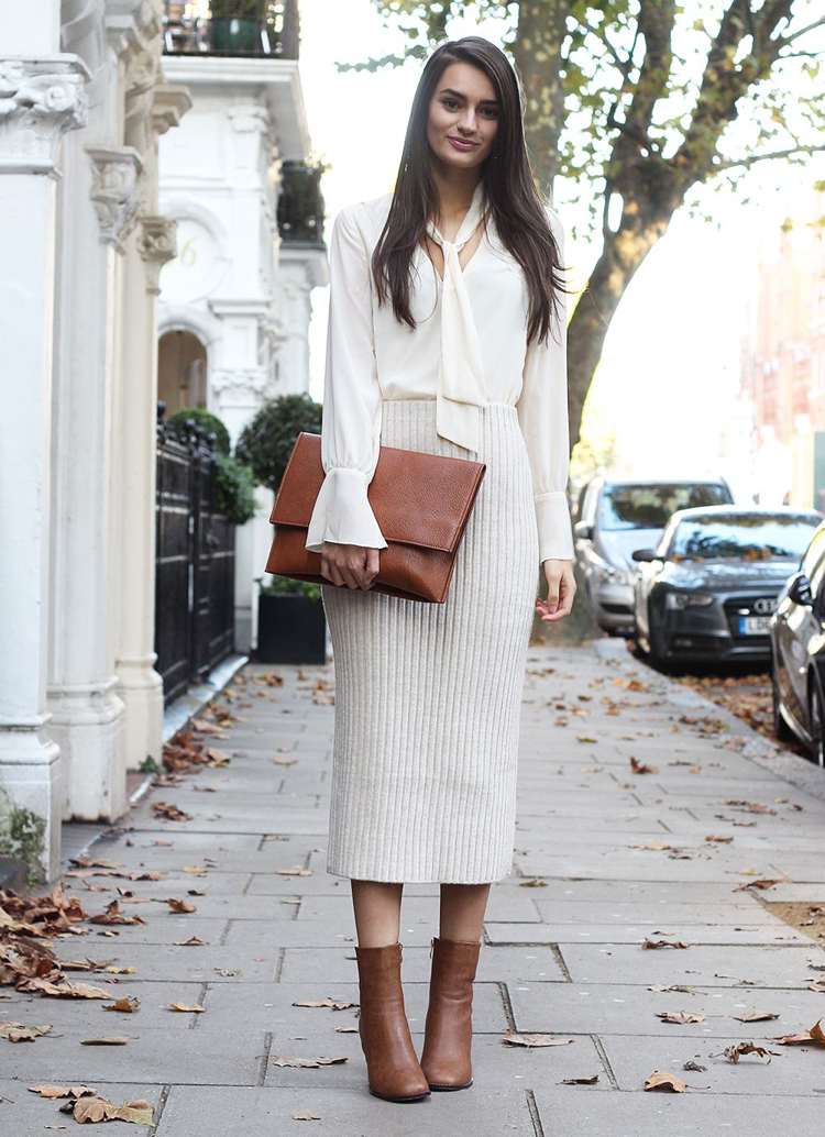 Saia de malha combina blusa de seda de comprimento médio em creme e branco com botas de couro marrom