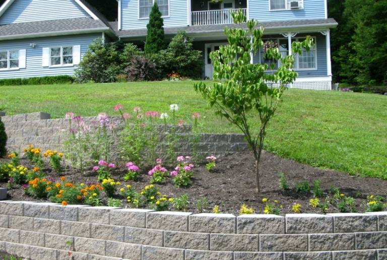Muro de contenção no jardim declive canteiro flores árvore pedra
