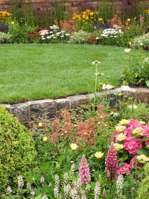 Jardim com gramado de parede de pedra natural apresenta design inglês