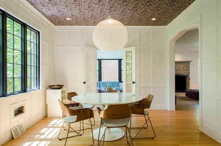 papel de parede no teto da sala de jantar paredes brancas mesa de jantar redonda cadeiras modernas