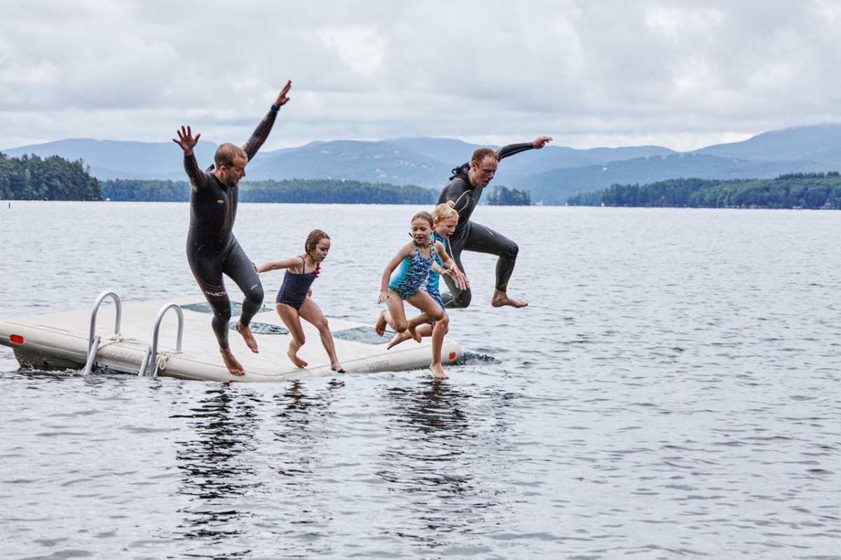Brincando com a família e crianças pulando da plataforma no lago