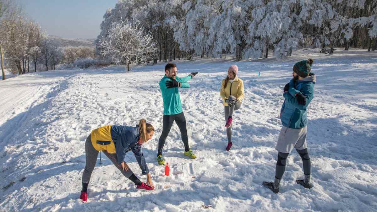 Grupo de jovens fazendo alongamento na neve nas férias de inverno