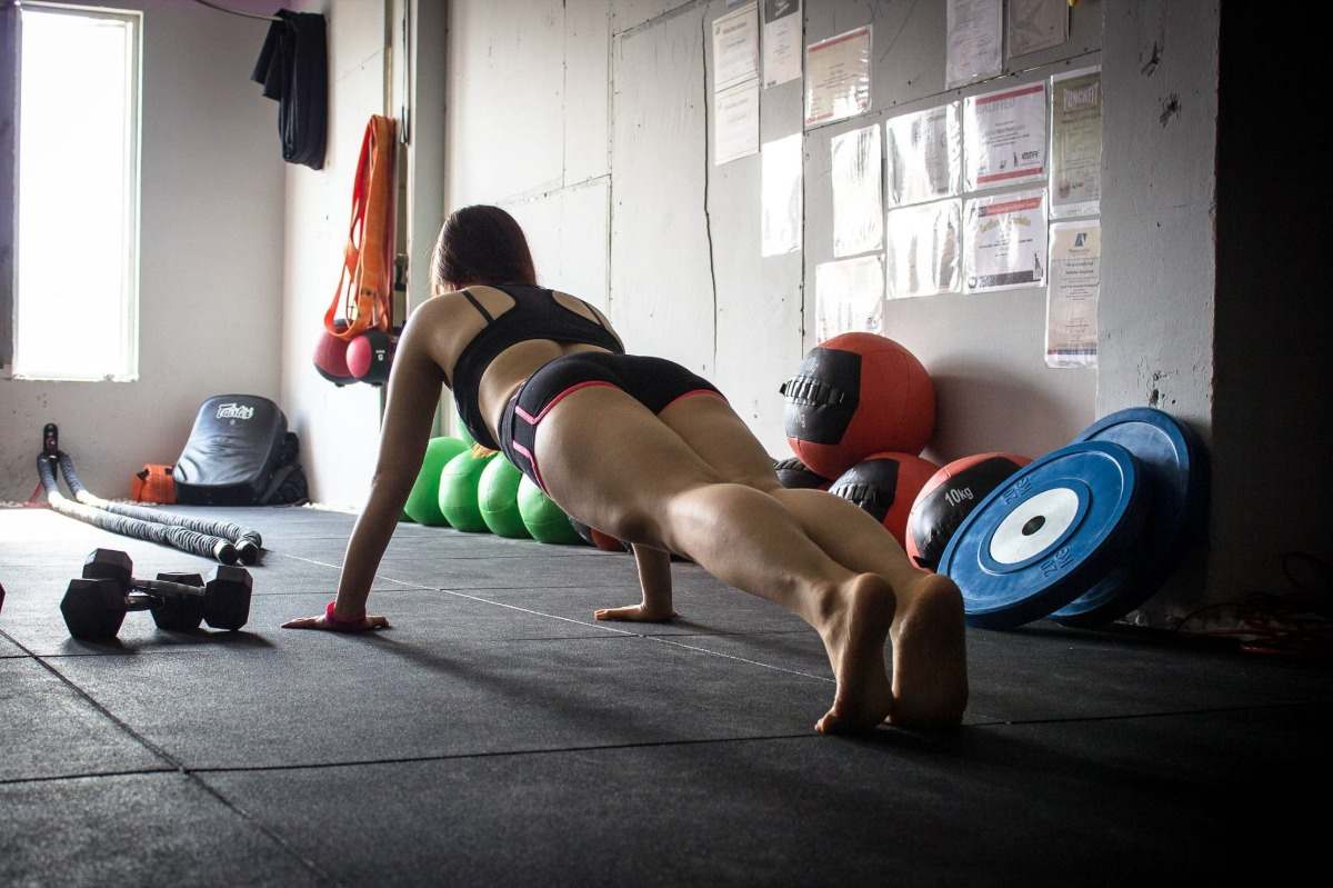 mulher na academia com roupas esportivas fazendo flexões