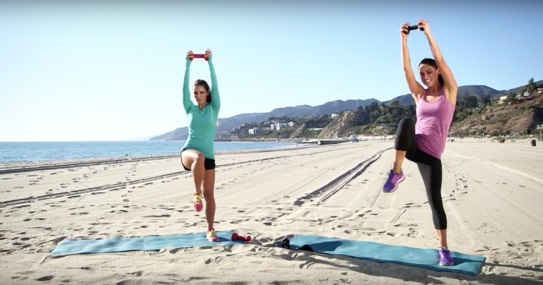 duas mulheres se exercitam na praia com rolos de espuma e pesos