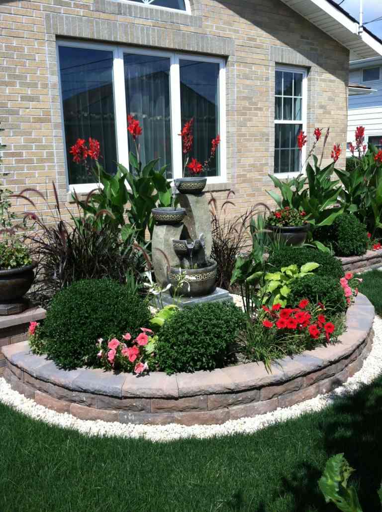Fronteira com design de jardim feito de buxo de pedra, petúnias, característica de água ensolarada