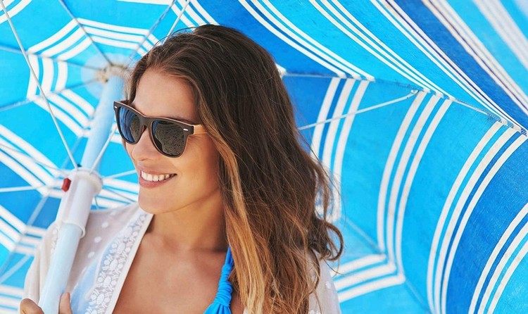 Uma mulher com guarda-sol na praia no verão