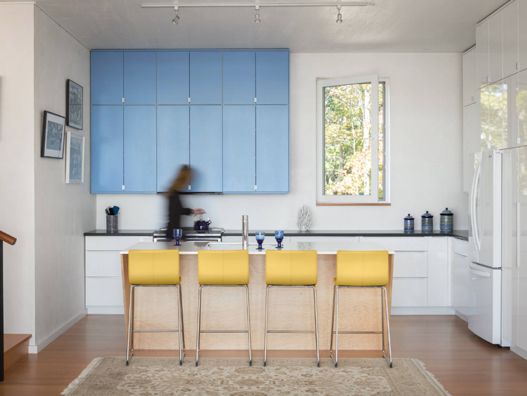 Móveis de parede de cozinha em azul pastel, cor de parede branca, bancos de bar amarelos