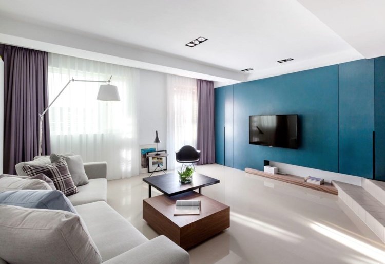 Cortinas lilás roxas da sala de estar com detalhes em azul na parede e piso bege