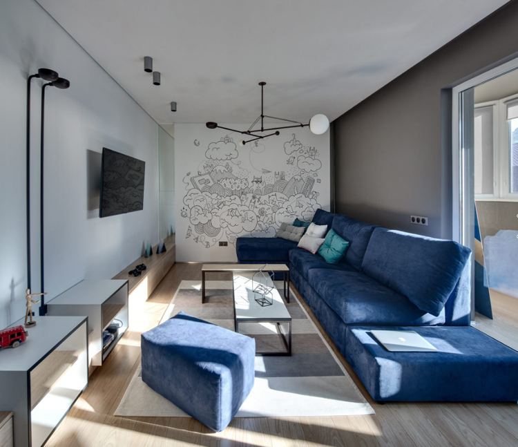 Paredes cinza e piso de madeira clara combinam com o sofá azul