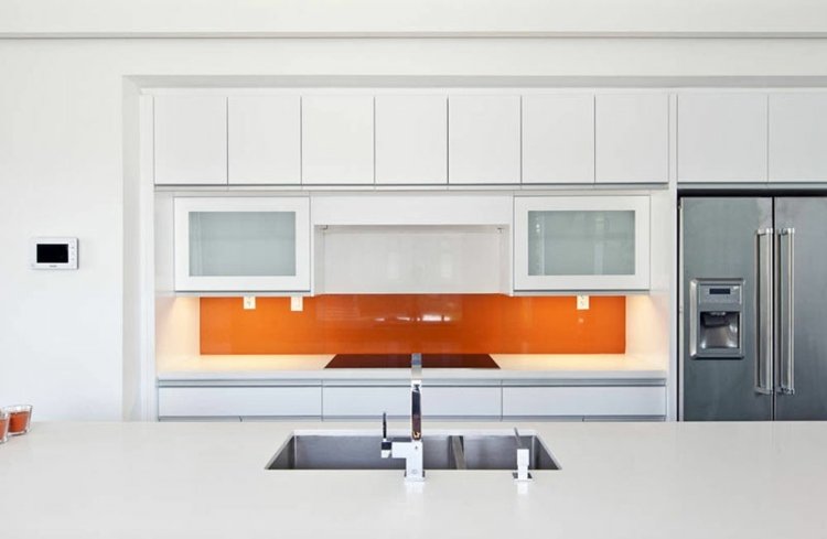 Parede traseira da cozinha laranja e cozinha branca feita de vidro para um visual moderno na sala