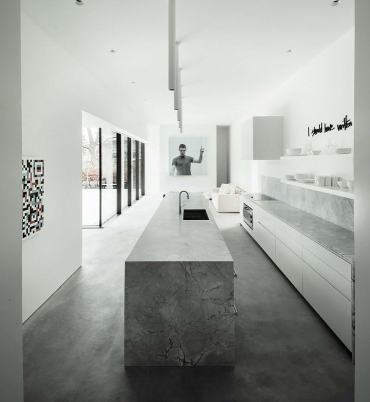 Pedra natural cinzenta e concreto exposto como piso para um design monocromático em um design de cozinha branco