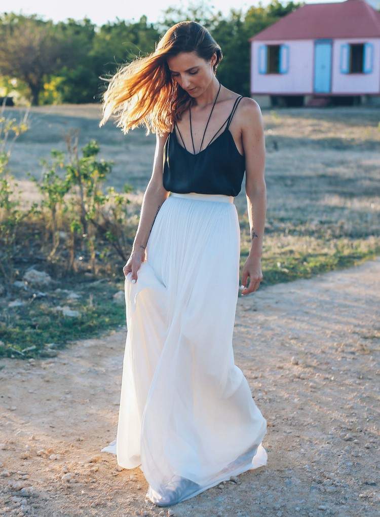 A saia longa branca combina alças finas com blusa preta no verão