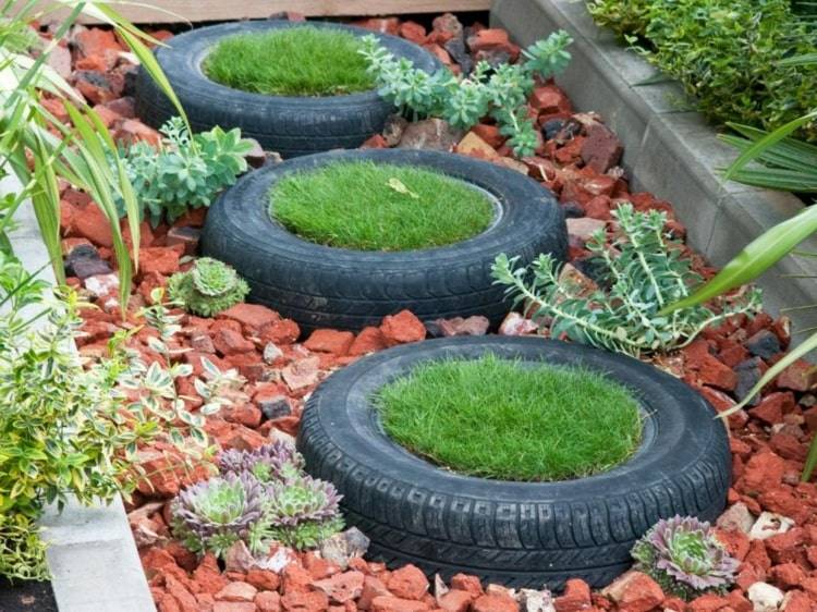 Ideia legal de jardim com pneus e gramado em um canteiro de pedras