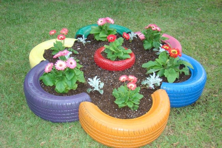 Canteiro de flores feito de pneus de carro em cores vivas como decoração de jardim