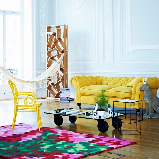 sofá amarelo tapete roxo colorido sala de estar