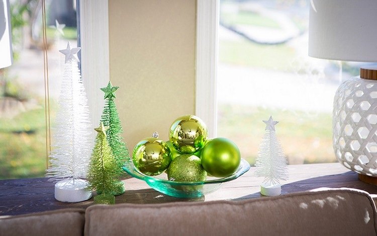 Decore a mesa de centro para o Natal com uma tigela com bolas de árvore de Natal verdes e árvores de Natal artificiais