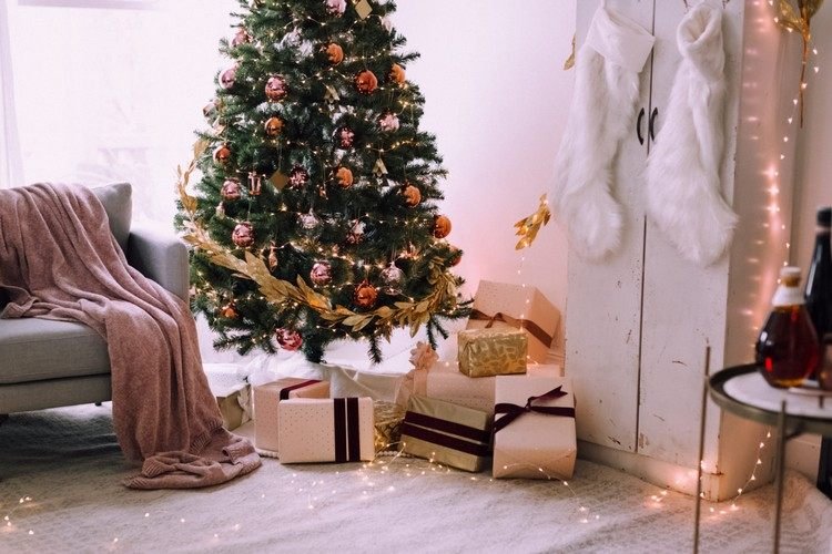 A sala de estar está decorada de forma festiva com ideias decorativas com luzes de fada e uma árvore de Natal com uma guirlanda de ouro