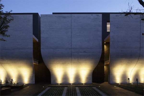 Parede de concreto com iluminação noturna em Breeze House