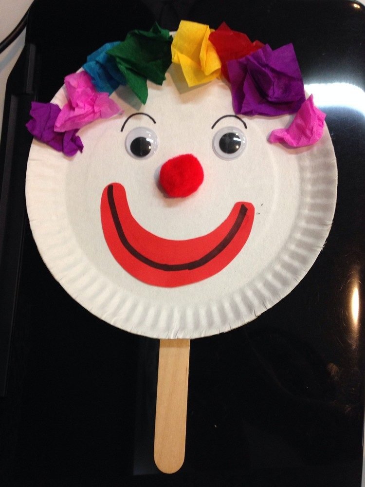 Palhaço brincando de boneca para carnaval usando pratos de papel e palitos de picolé