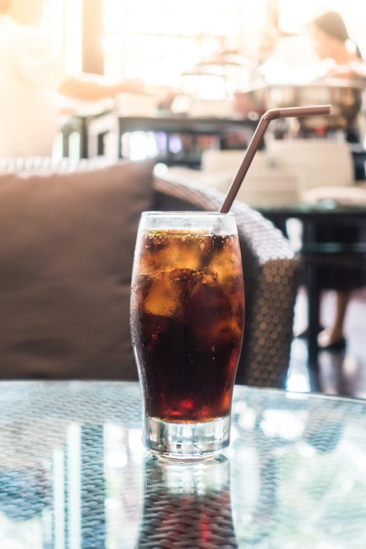 cubos de gelo resfriam um copo com coca-cola no café